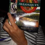 Canoe camper hammock-reading Kevin Callan's "Once Around Algonquin"